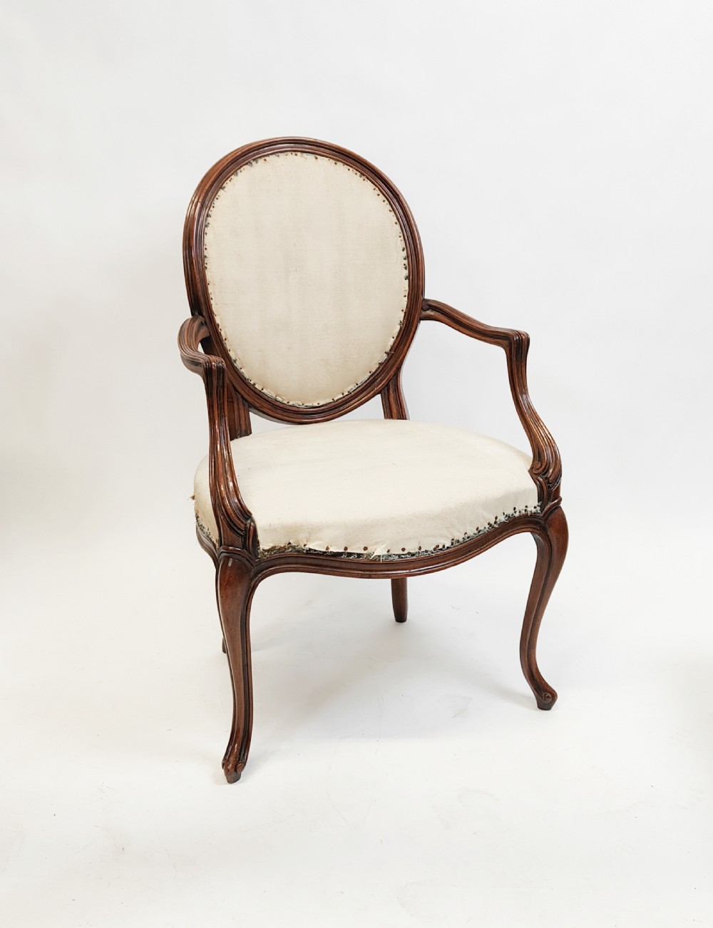 A 19th-century French open armchair featuring a carved wooden frame, medallion backrest, cabriole legs, and light cream upholstery. View X