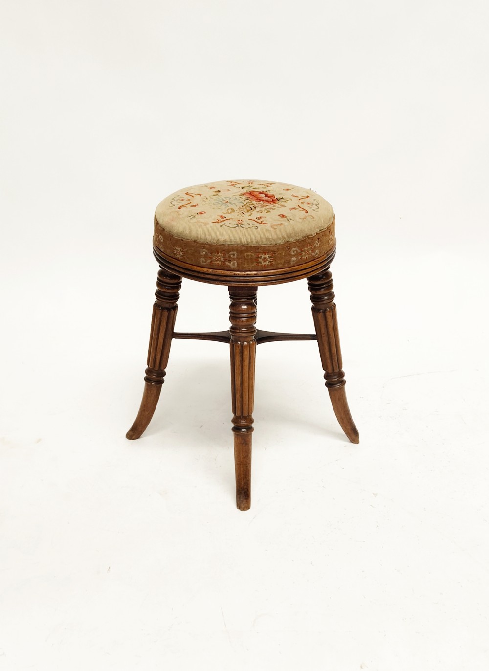 A Regency mahogany piano stool featuring a circular floral needlepoint upholstered seat, a wooden thread swivel mechanism, and four fluted legs. View II