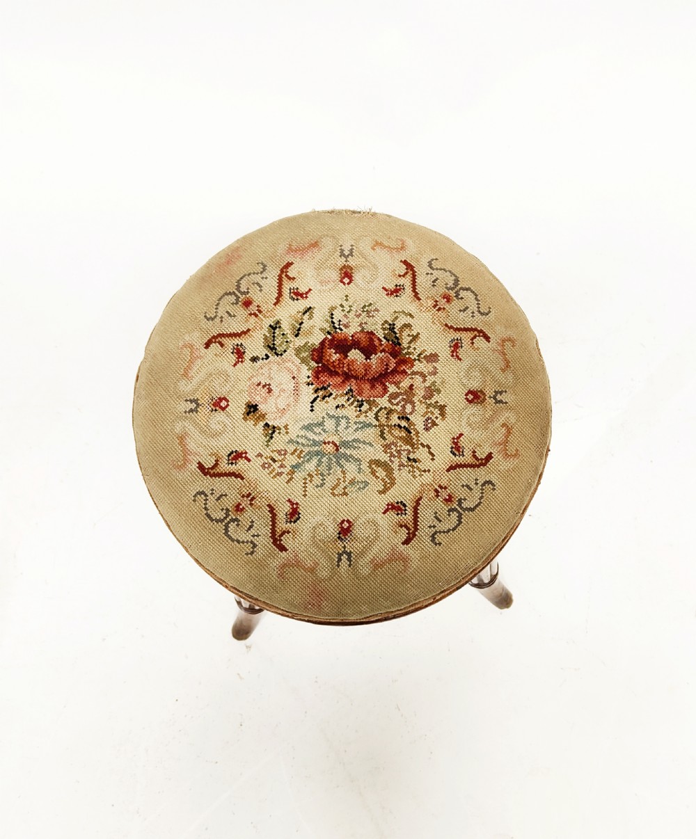 A Regency mahogany piano stool featuring a circular floral needlepoint upholstered seat, a wooden thread swivel mechanism, and four fluted legs. View VIII