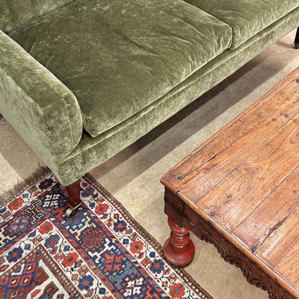 A low 19th-century Indian Takhat coffee table crafted from warm brown timber featuring a carved scalloped apron, iron corner brackets, and red turned legs. View III