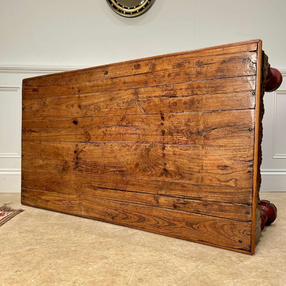 A low 19th-century Indian Takhat coffee table crafted from warm brown timber featuring a carved scalloped apron, iron corner brackets, and red turned legs. View IV