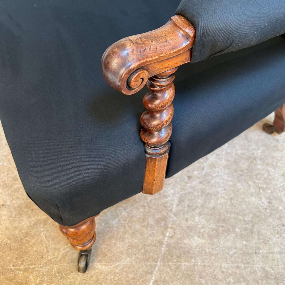 A 19th-century Victorian open armchair featuring black button-tufted fabric upholstery, barley twist wooden arm supports and front legs, and brass castors. View II