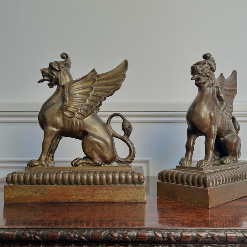 A pair of 19th-century bronzed metal griffin sculptures facing each other, mounted on stepped rectangular bases. View II