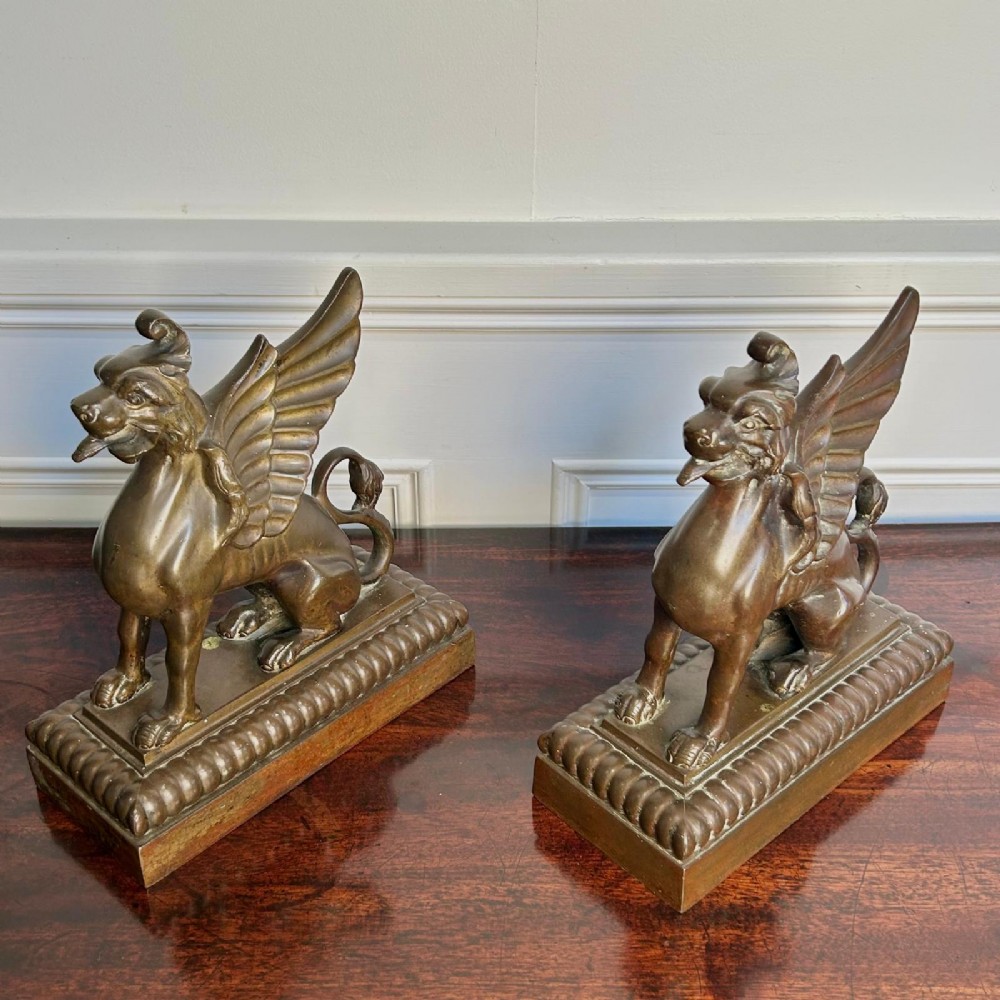 A pair of 19th-century bronzed metal griffin sculptures facing each other, mounted on stepped rectangular bases. View V
