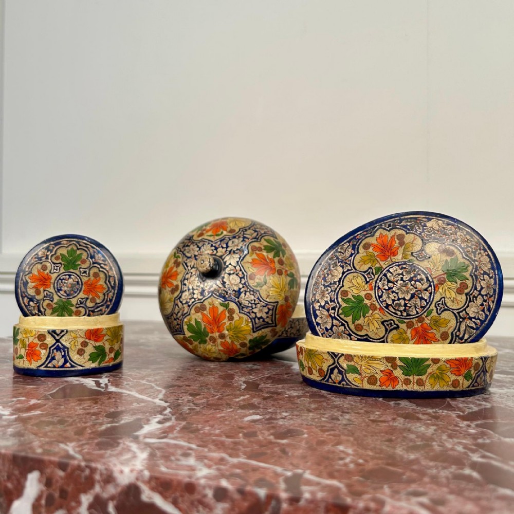 A set of three circular hand-painted Kashmiri papier-mache lidded pots adorned with intricate blue, gold, and foliage patterns. View IV