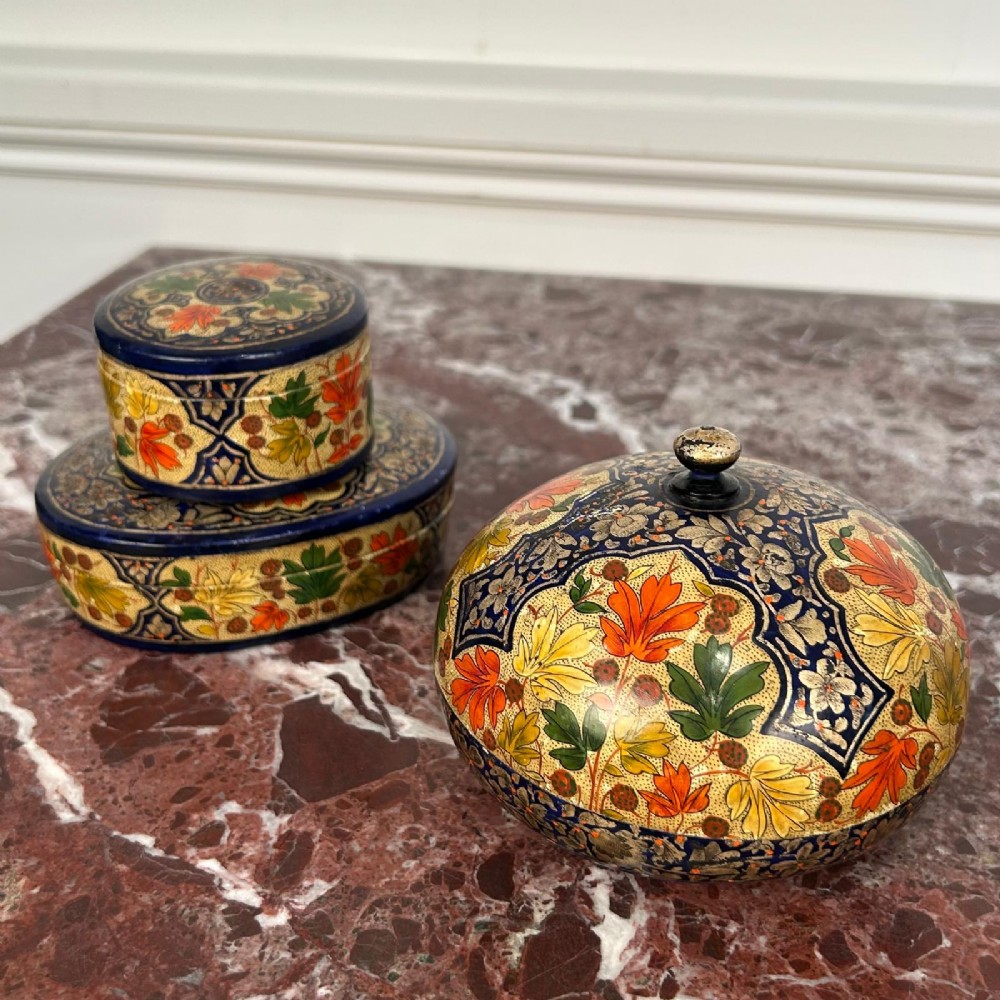 A set of three circular hand-painted Kashmiri papier-mache lidded pots adorned with intricate blue, gold, and foliage patterns. View VI