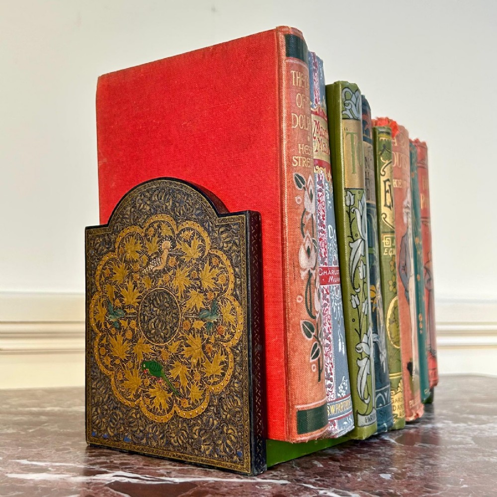 A pair of arched Kashmiri bookends decorated with intricate gold floral patterns, chinar leaves, and colourful painted birds on a dark background. View II