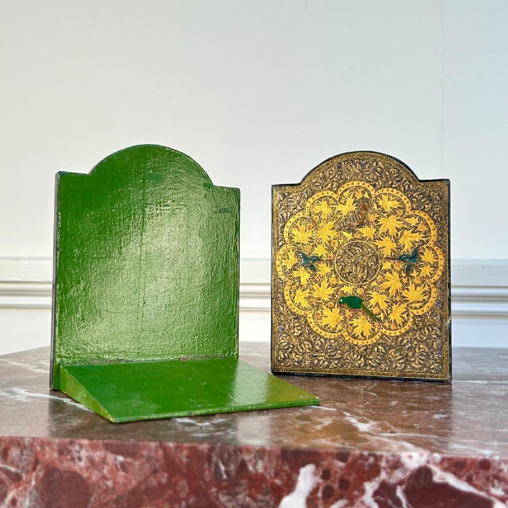 A pair of arched Kashmiri bookends decorated with intricate gold floral patterns, chinar leaves, and colourful painted birds on a dark background. View V