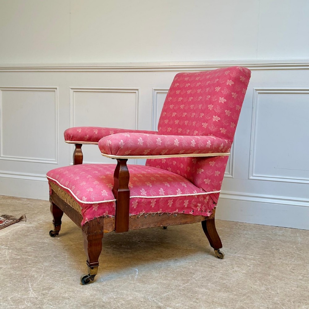 A nineteenth-century Arts and Crafts armchair featuring pink floral fabric upholstery, turned mahogany front legs, and brass castors. View II