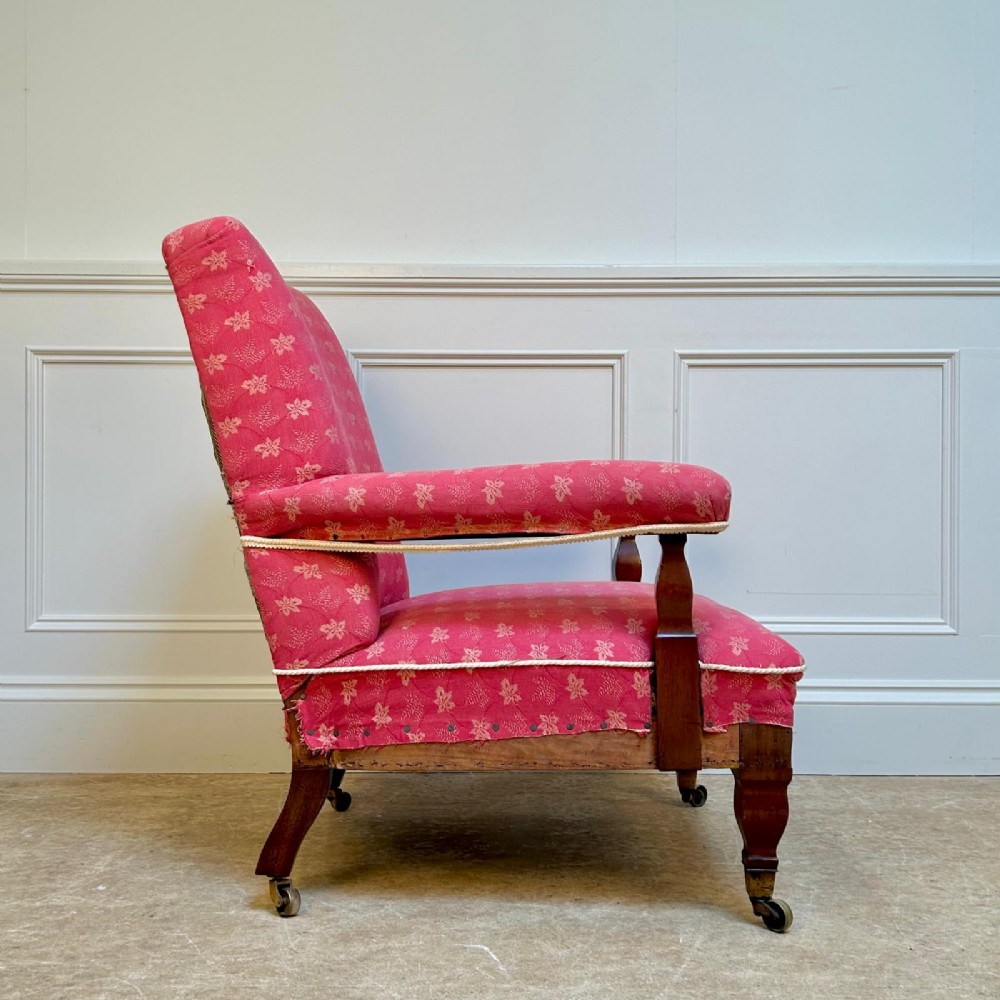 A nineteenth-century Arts and Crafts armchair featuring pink floral fabric upholstery, turned mahogany front legs, and brass castors. View III
