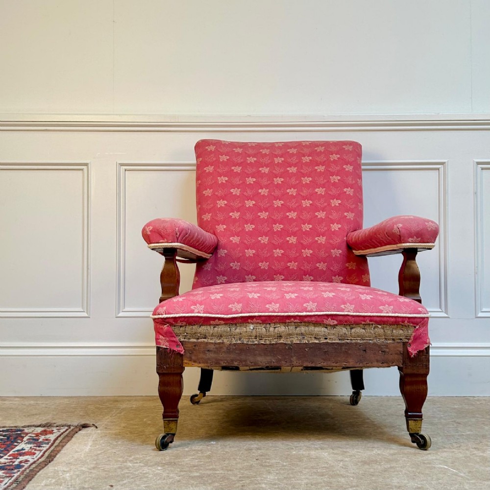 A nineteenth-century Arts and Crafts armchair featuring pink floral fabric upholstery, turned mahogany front legs, and brass castors. View IV