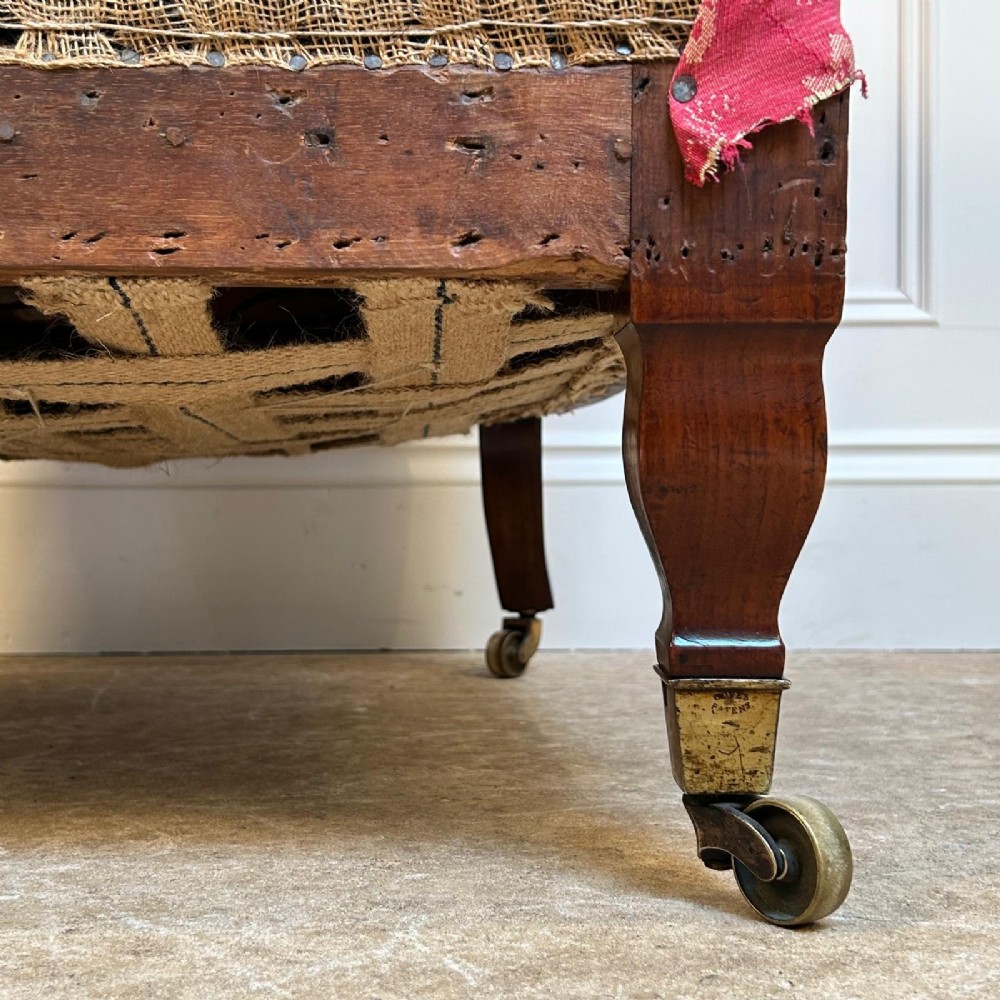 A nineteenth-century Arts and Crafts armchair featuring pink floral fabric upholstery, turned mahogany front legs, and brass castors. View V