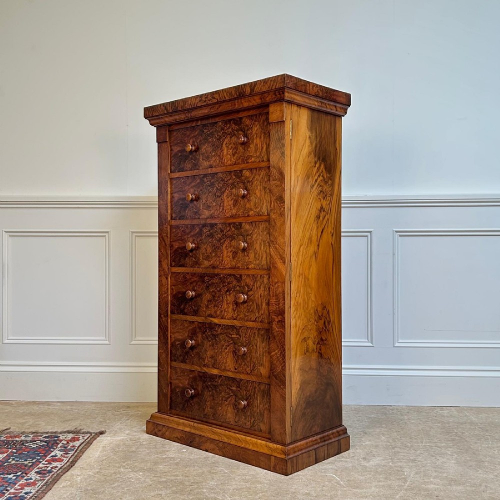A 19th-century Victorian burr walnut Wellington chest featuring six graduated drawers with double turned wooden knobs and a hinged side locking stile on a solid plinth base. View II