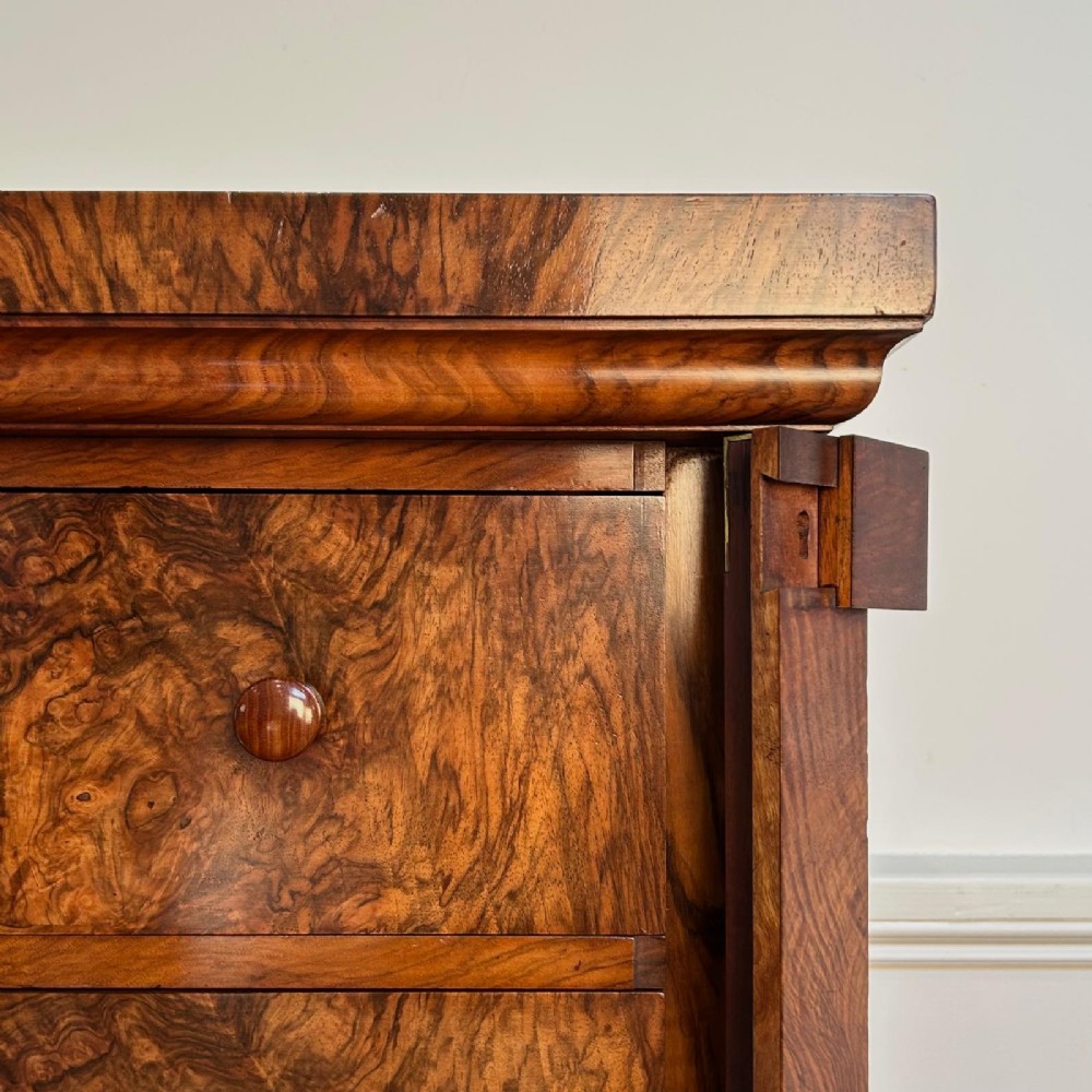 A 19th-century Victorian burr walnut Wellington chest featuring six graduated drawers with double turned wooden knobs and a hinged side locking stile on a solid plinth base. View V