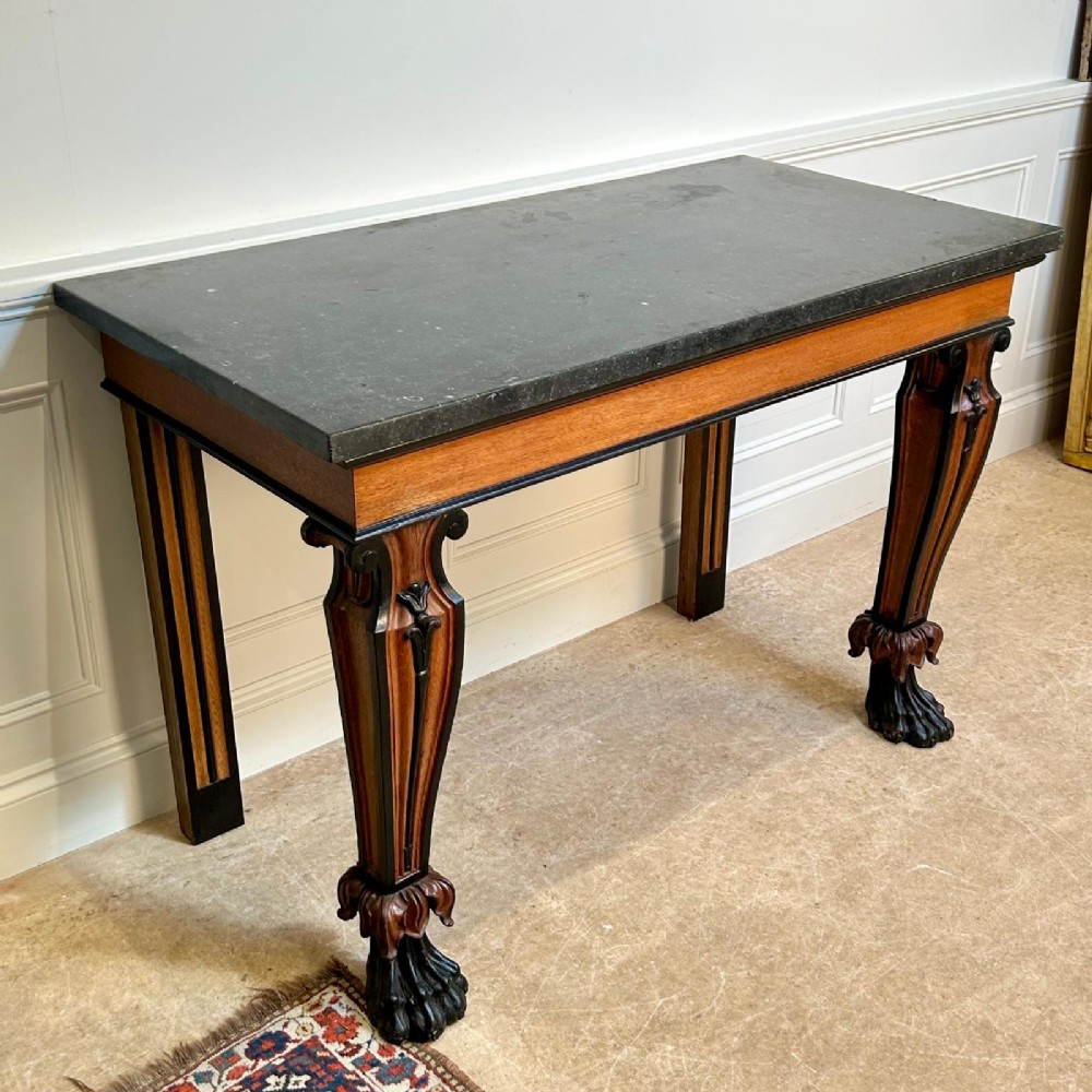 A Regency oak console table featuring a dark stone top, ebonised trim, and front legs carved with acanthus leaves and lion paw feet. View V