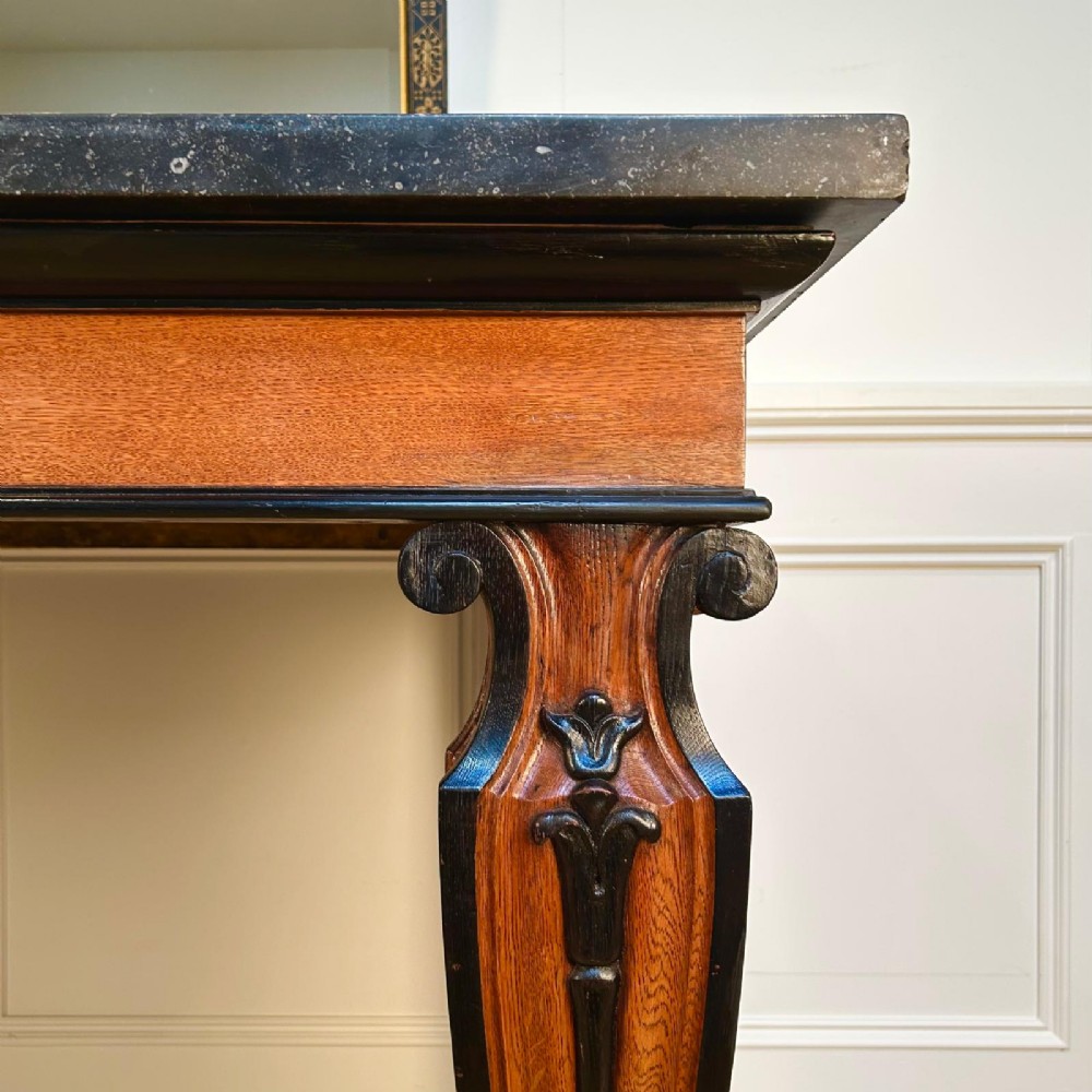 A Regency oak console table featuring a dark stone top, ebonised trim, and front legs carved with acanthus leaves and lion paw feet. View VI