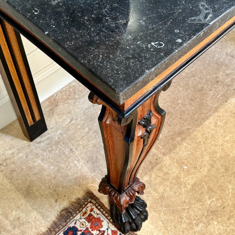 A Regency oak console table featuring a dark stone top, ebonised trim, and front legs carved with acanthus leaves and lion paw feet. View VII