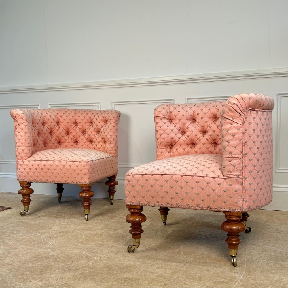 A pair of 19th-century corner armchairs upholstered in pink diamond-patterned fabric featuring button-tufted rounded backs and turned oak legs on brass castors. View II