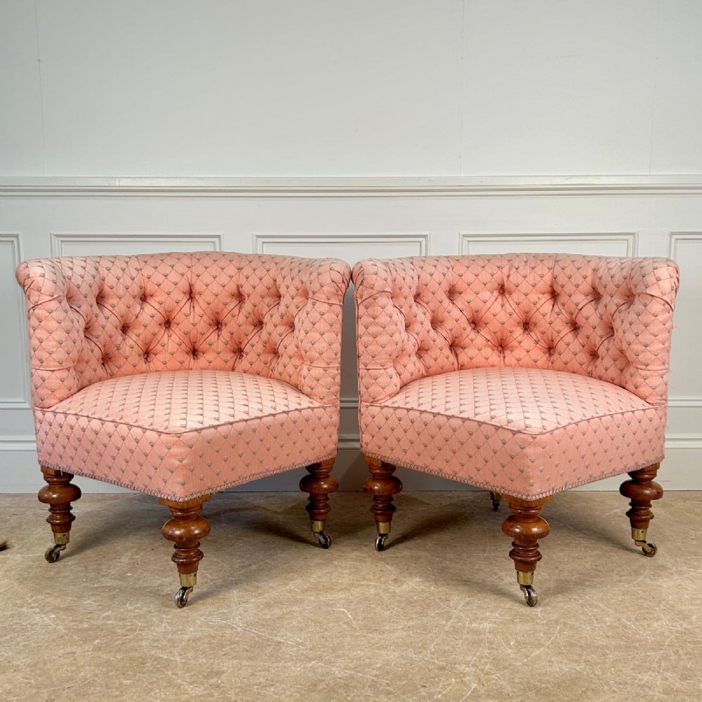 A pair of 19th-century corner armchairs upholstered in pink diamond-patterned fabric featuring button-tufted rounded backs and turned oak legs on brass castors. View III