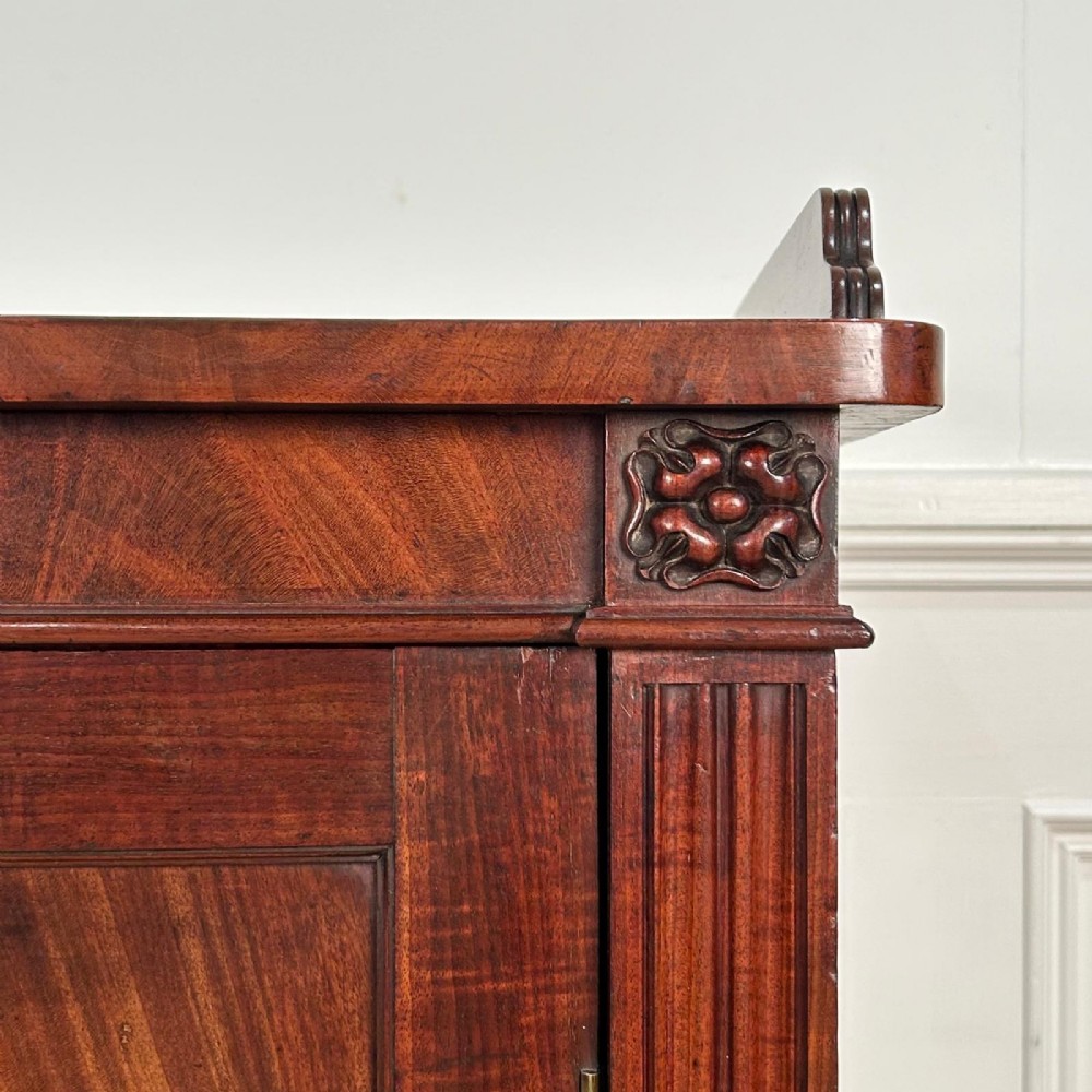 A George IV flame mahogany dwarf secretaire cabinet featuring reeded pilasters, two panelled doors, and turned bun feet. View VIII