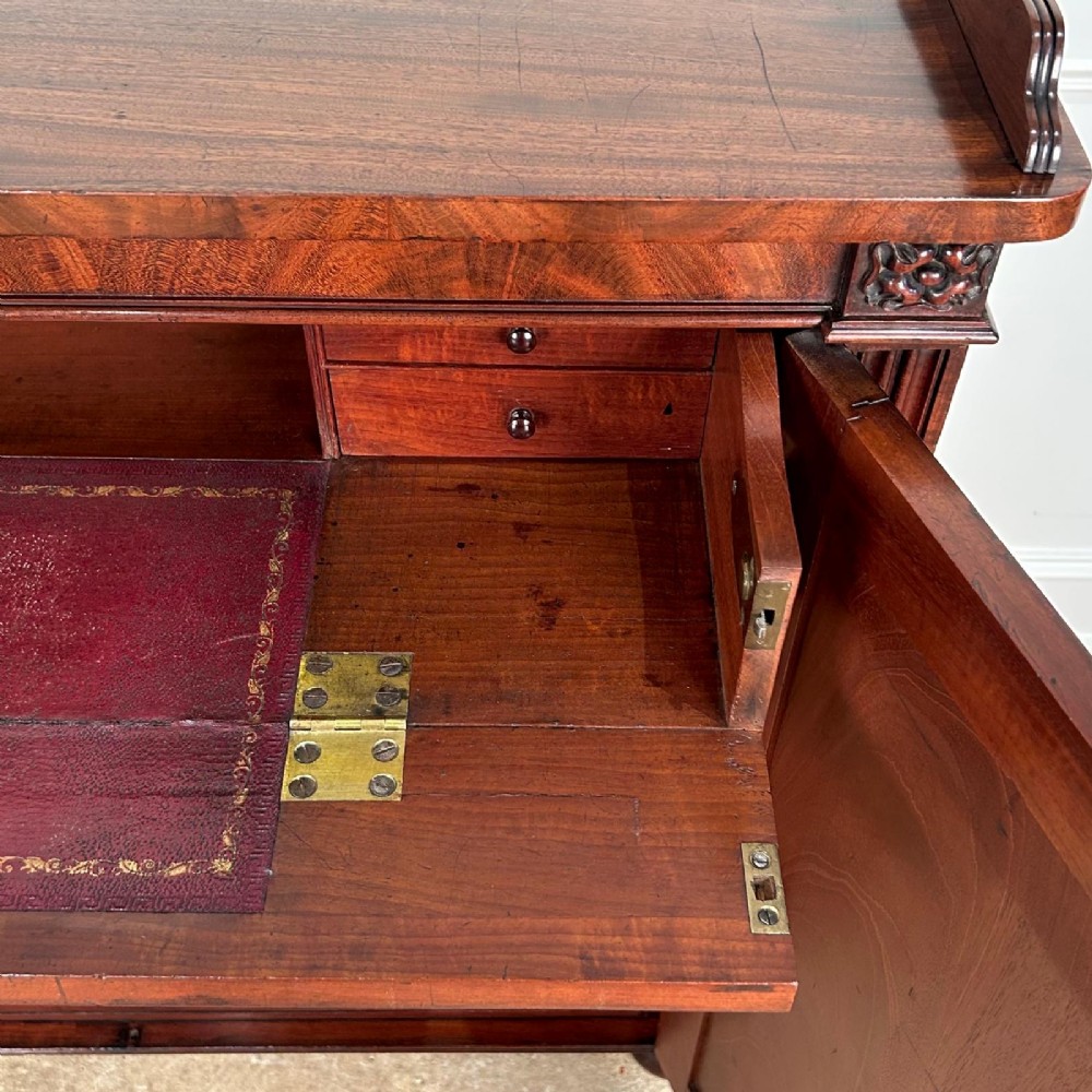 A George IV flame mahogany dwarf secretaire cabinet featuring reeded pilasters, two panelled doors, and turned bun feet. View IX
