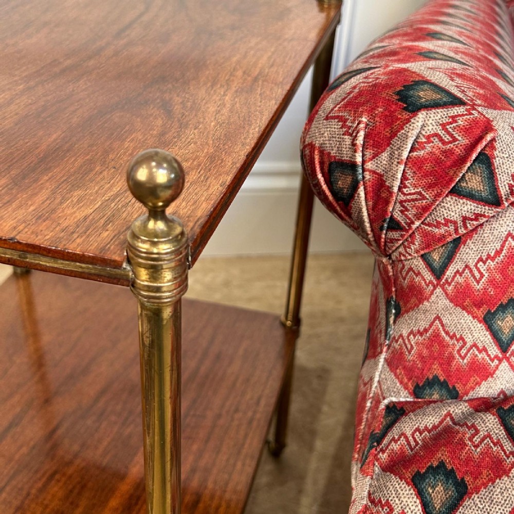 An Edwardian two-tier side table with polished square rosewood shelves held by slender brass legs with finials and castors. View V