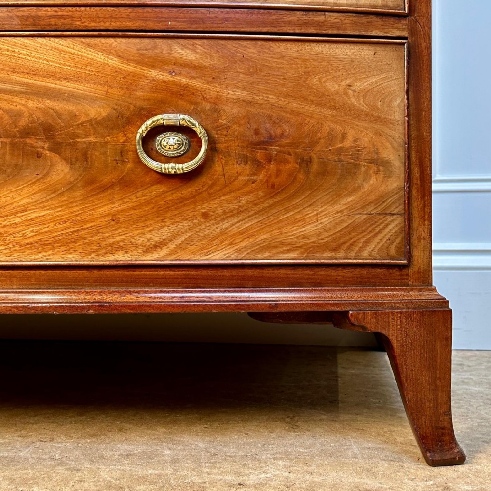 A late 18th-century Georgian flame mahogany bowfront chest of drawers featuring four graduated drawers with brass handles and splayed bracket feet. View II