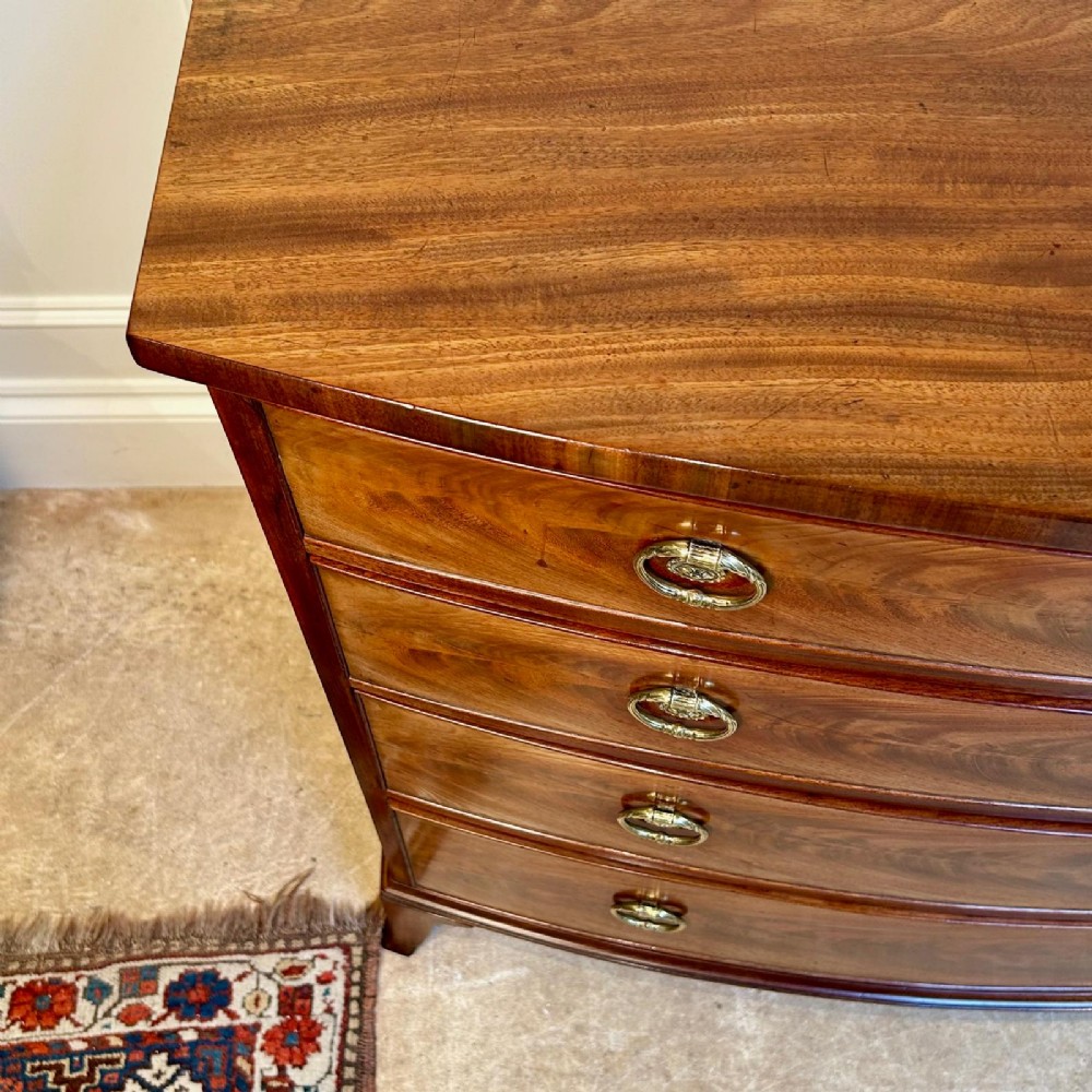 A late 18th-century Georgian flame mahogany bowfront chest of drawers featuring four graduated drawers with brass handles and splayed bracket feet. View III
