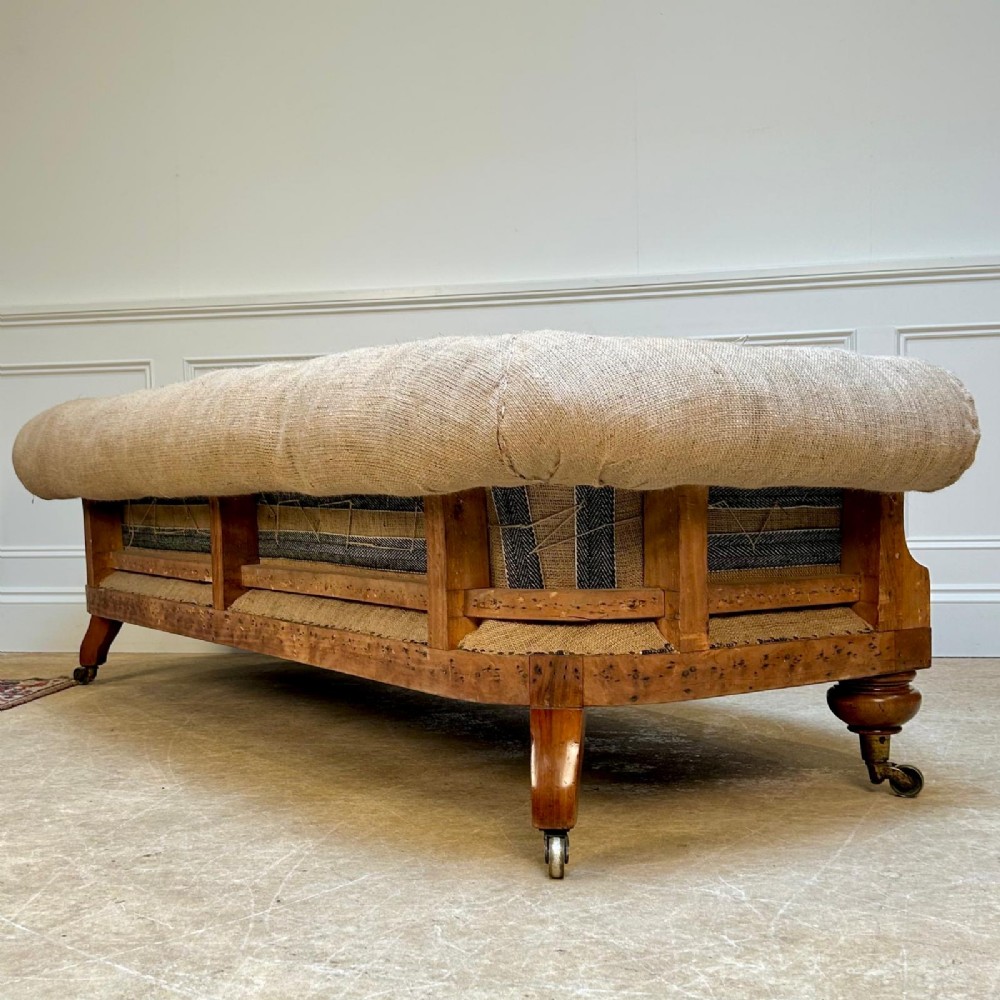A nineteenth-century country house sofa featuring a buttoned hessian back, dark navy seat cushions, rolled arms, and turned wooden legs on brass castors. View IV