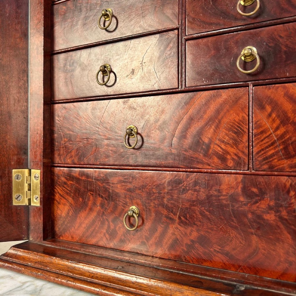An 18th-century mahogany tabletop collectors cabinet featuring double doors that open to reveal multiple graduated internal drawers with small brass ring handles. View III