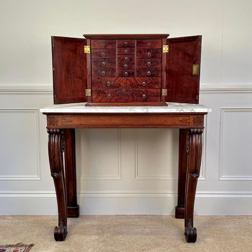 An 18th-century mahogany tabletop collectors cabinet featuring double doors that open to reveal multiple graduated internal drawers with small brass ring handles. View V