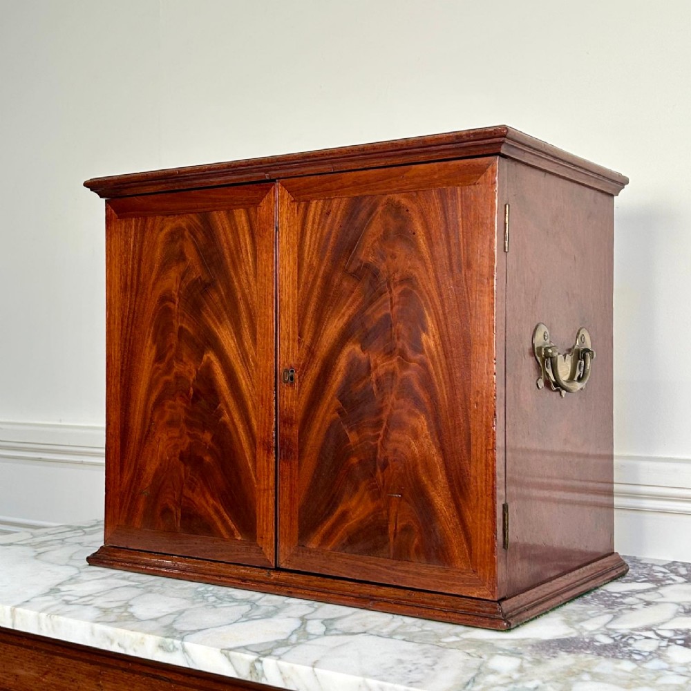 An 18th-century mahogany tabletop collectors cabinet featuring double doors that open to reveal multiple graduated internal drawers with small brass ring handles. View VI