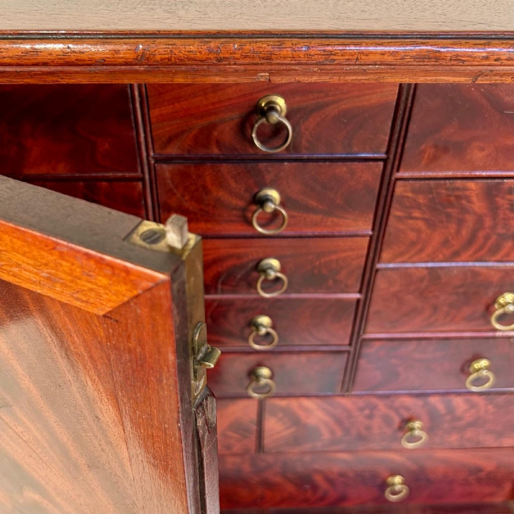 An 18th-century mahogany tabletop collectors cabinet featuring double doors that open to reveal multiple graduated internal drawers with small brass ring handles. View VII