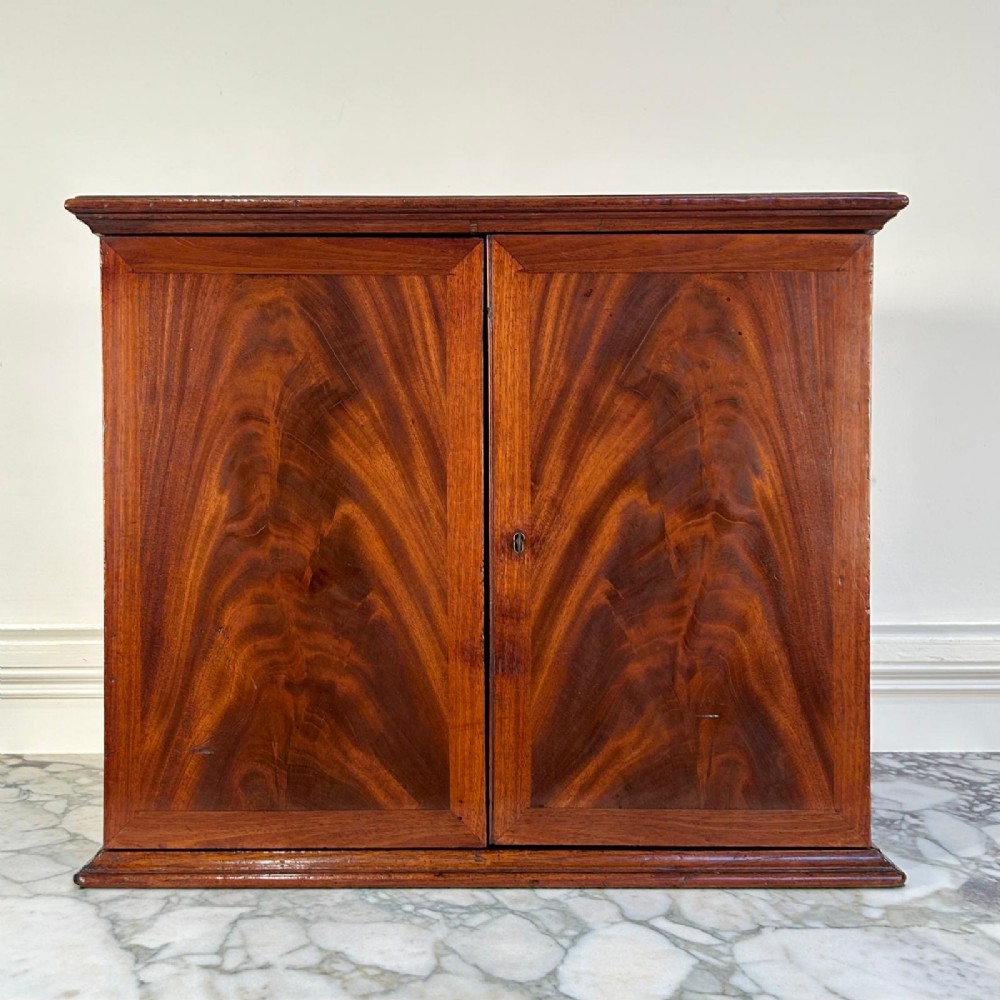 An 18th-century mahogany tabletop collectors cabinet featuring double doors that open to reveal multiple graduated internal drawers with small brass ring handles. View VIII