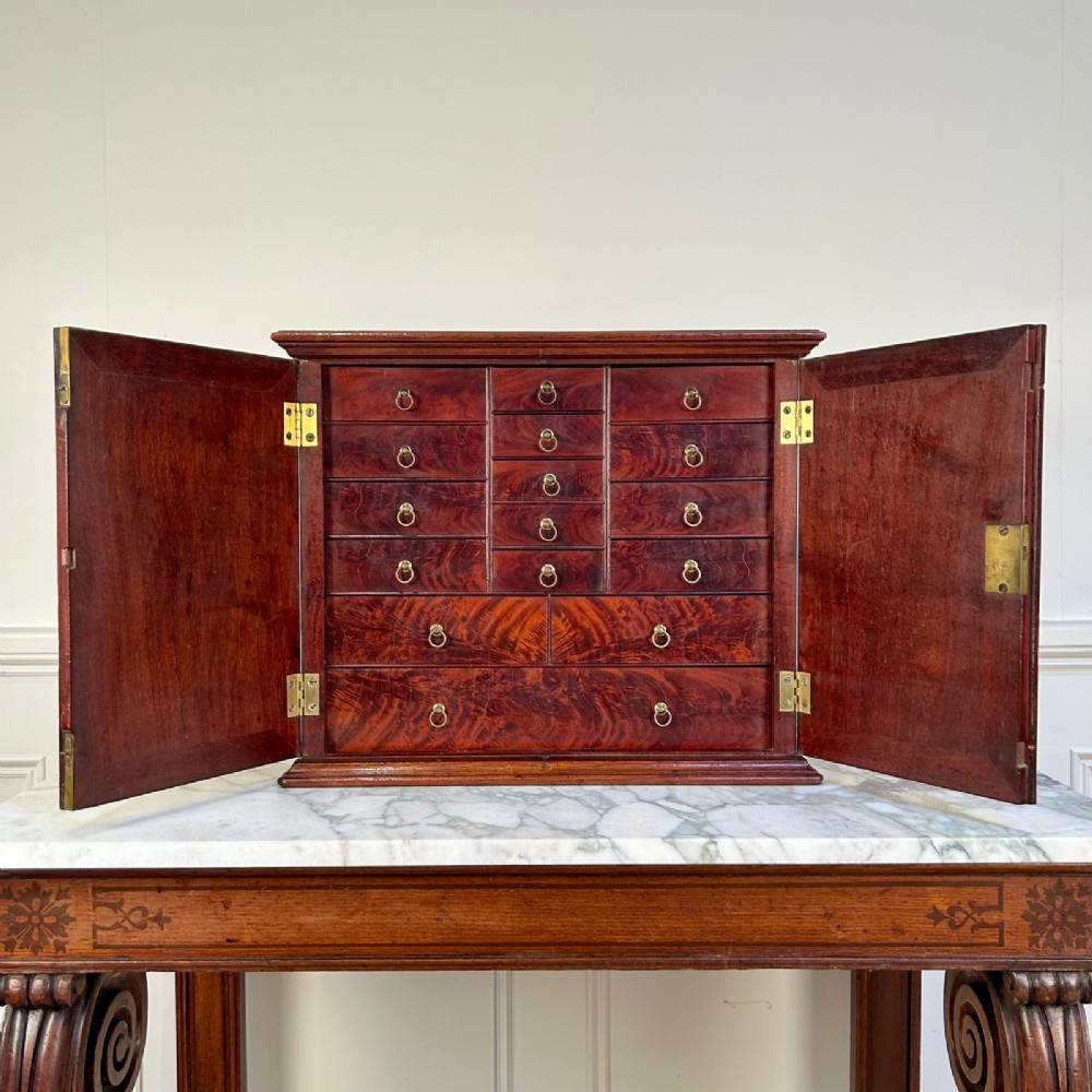 An 18th-century mahogany tabletop collectors cabinet featuring double doors that open to reveal multiple graduated internal drawers with small brass ring handles. View IX