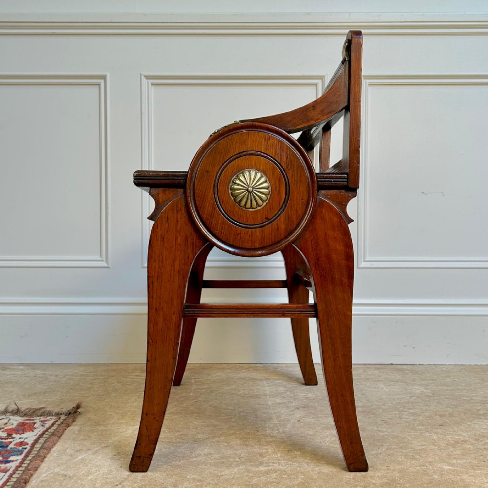 A 19th-century Victorian walnut hall bench featuring a spindle gallery back, raised arms with brass shell mounts, and reeded legs. View IV
