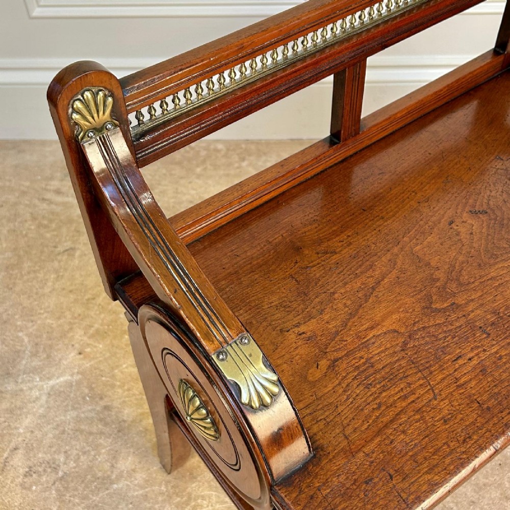 A 19th-century Victorian walnut hall bench featuring a spindle gallery back, raised arms with brass shell mounts, and reeded legs. View V