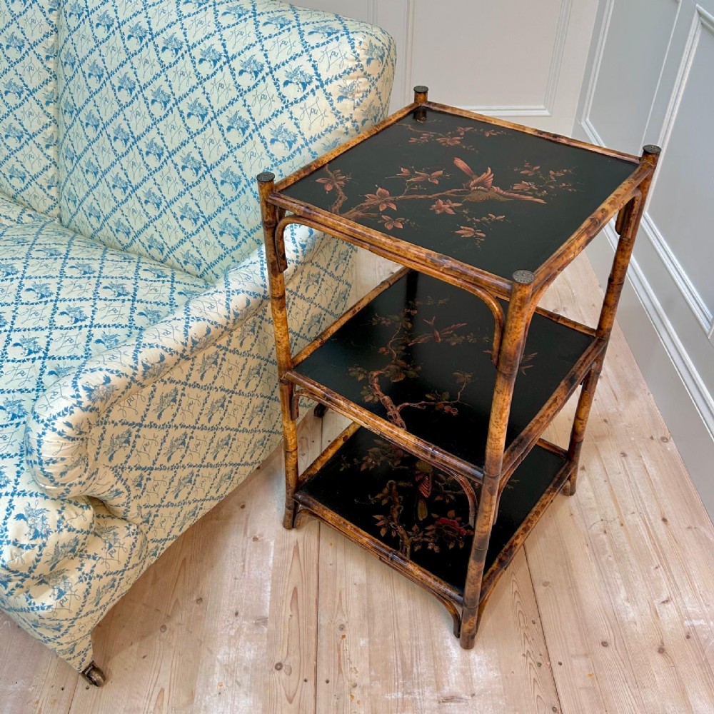 A three-tiered bamboo etagere featuring dark lacquered square shelf panels painted with bird and botanical designs. View V