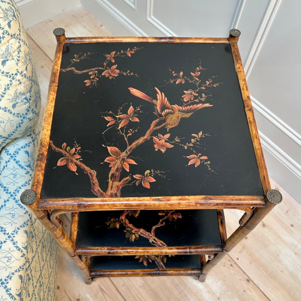 A three-tiered bamboo etagere featuring dark lacquered square shelf panels painted with bird and botanical designs. View VI