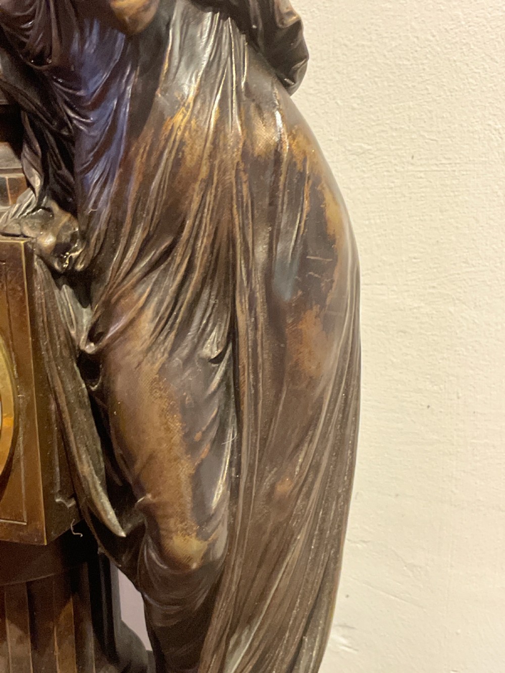 A late 19th-century French dark patinated bronze mantel clock depicting a classical draped female figure leaning upon a column containing a round dial with Roman numerals. View VII