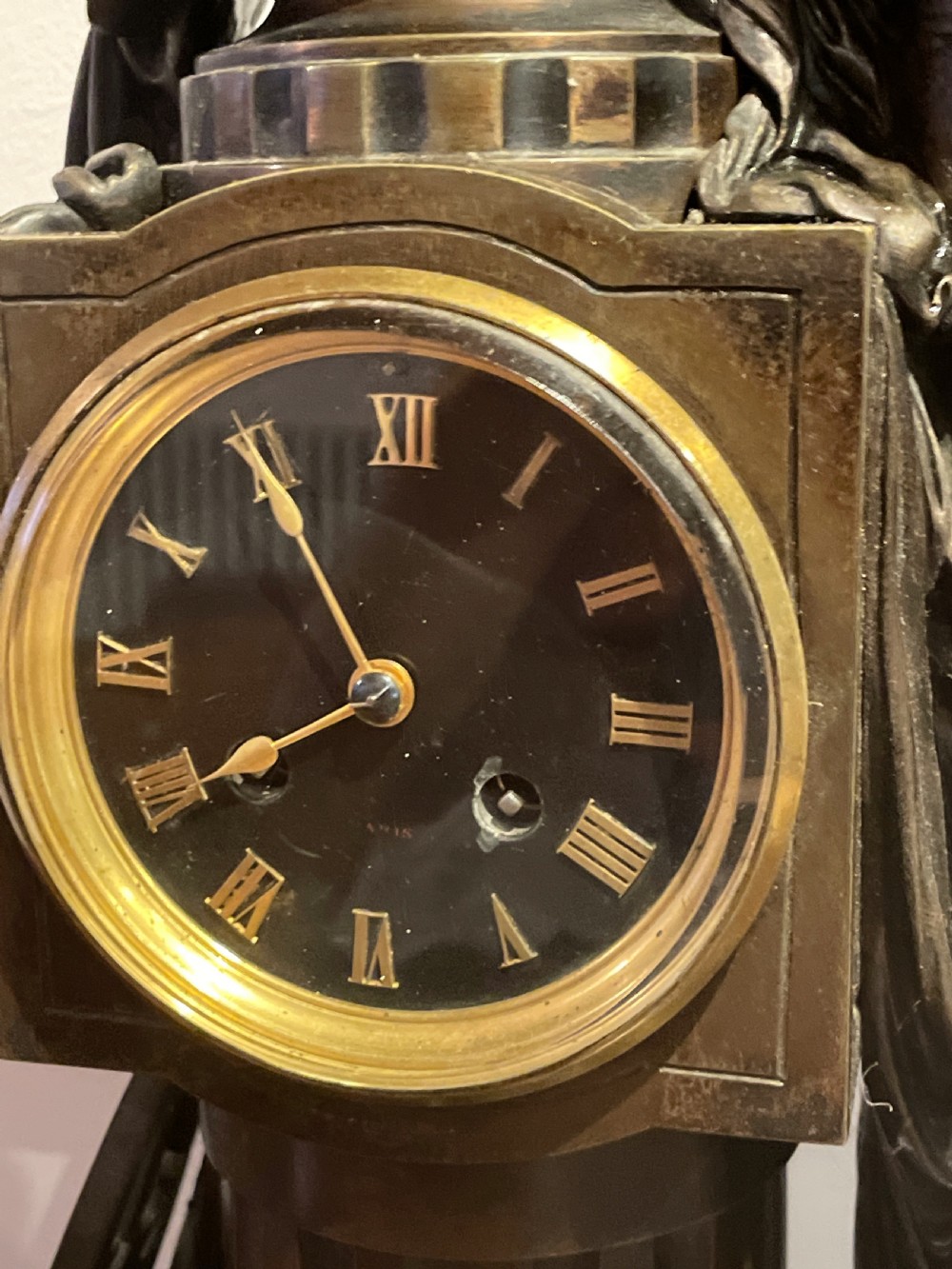 A late 19th-century French dark patinated bronze mantel clock depicting a classical draped female figure leaning upon a column containing a round dial with Roman numerals. View IX