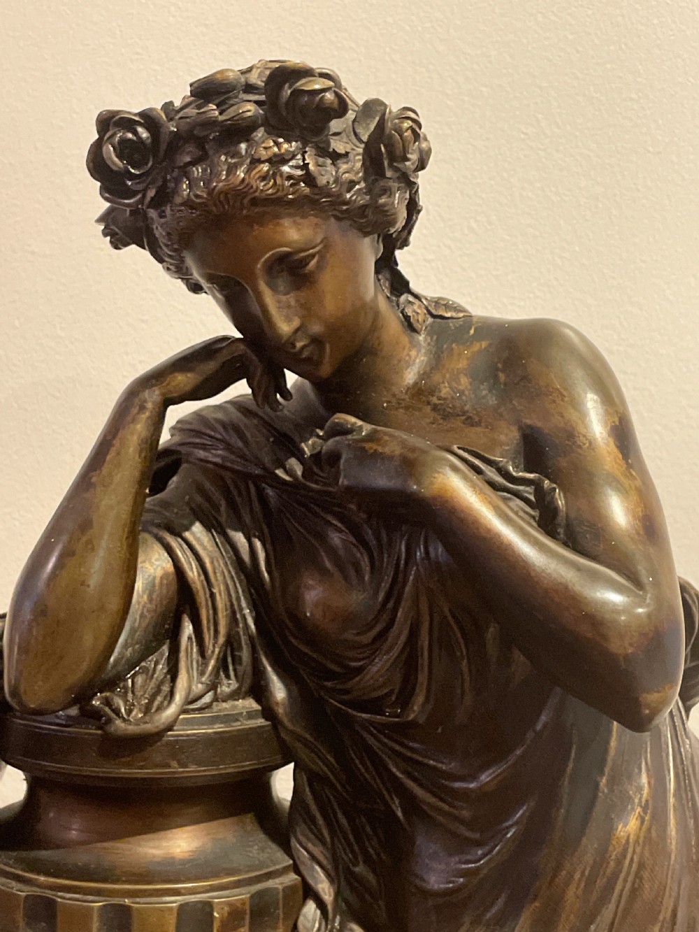 A late 19th-century French dark patinated bronze mantel clock depicting a classical draped female figure leaning upon a column containing a round dial with Roman numerals. View X