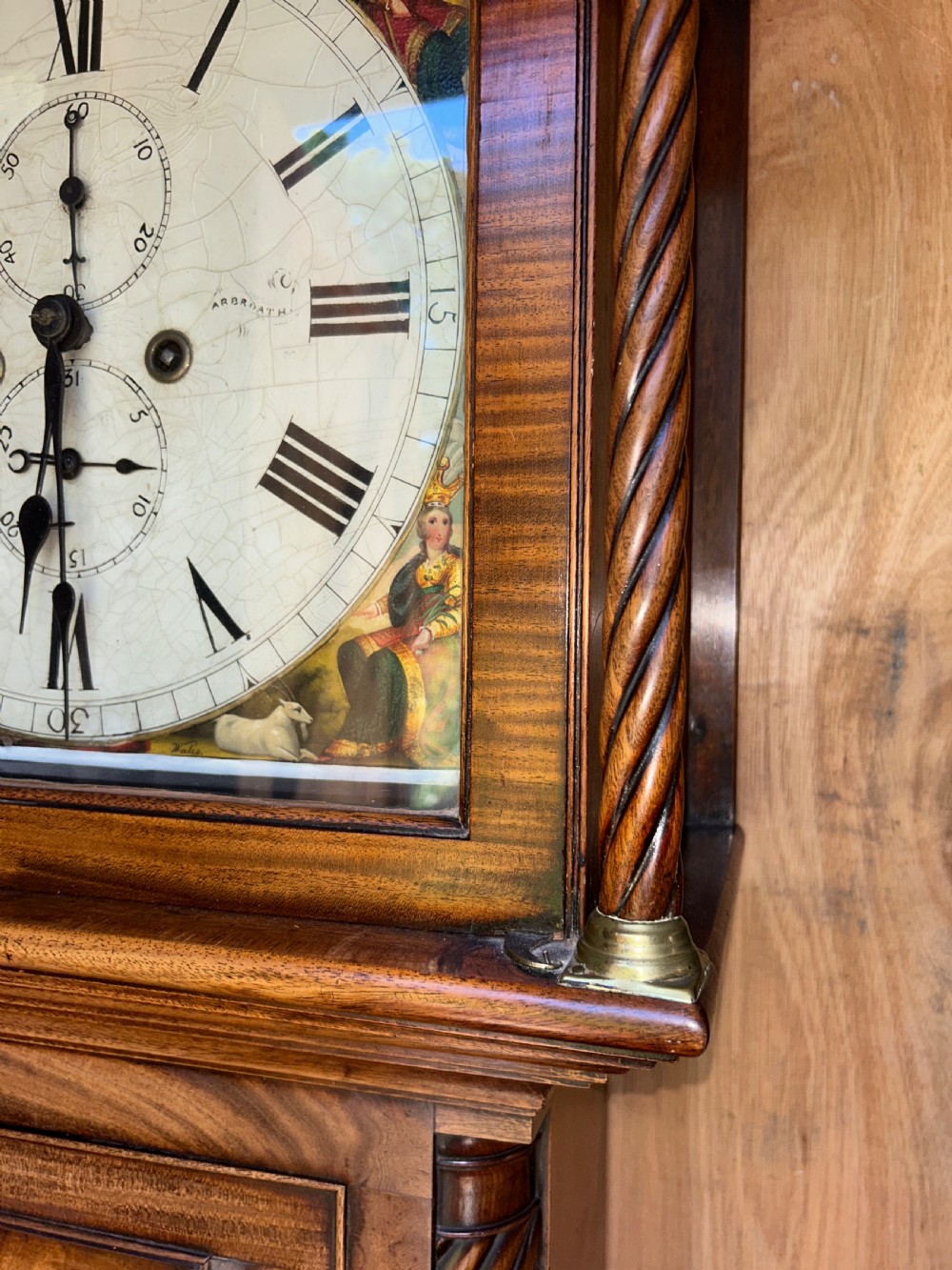 An upright wooden longcase clock featuring a carved swan-neck pediment, a painted dial face, spiral barley twist columns, and a rectangular trunk door. View VIII