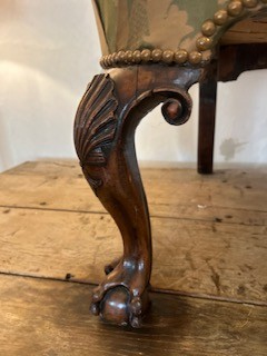 An antique George II wing armchair upholstered in patterned green damask fabric with carved walnut cabriole legs. View II