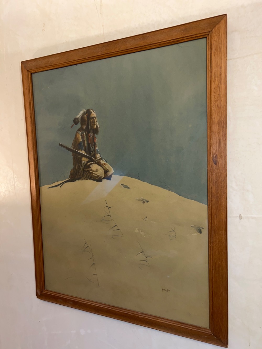 A framed watercolour painting depicting a Native American figure seated on a grassy mound holding a rifle against a muted blue sky. View IV