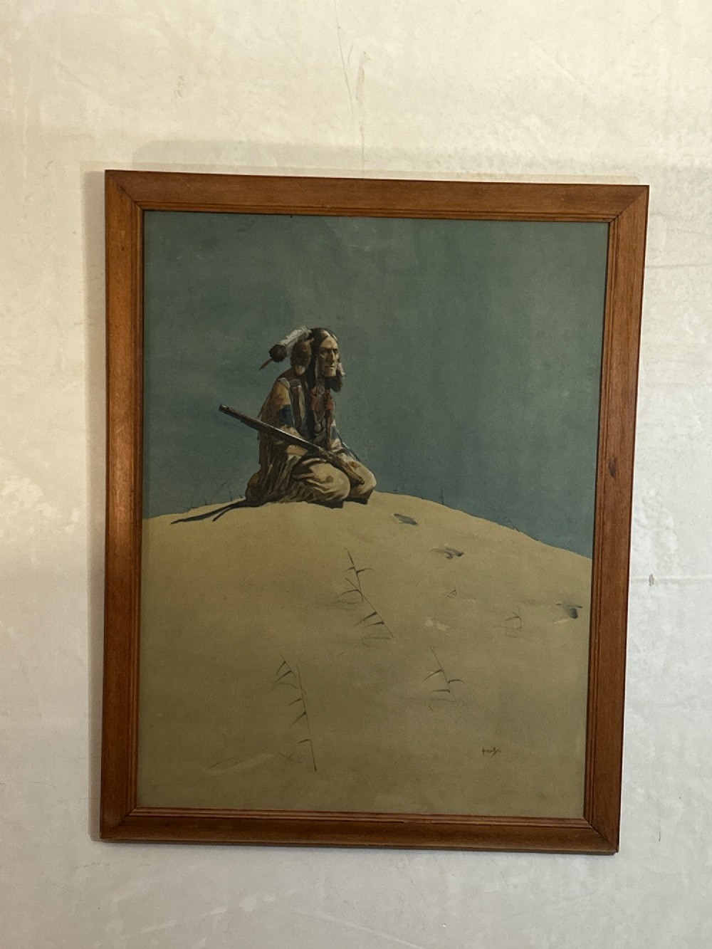 A framed watercolour painting depicting a Native American figure seated on a grassy mound holding a rifle against a muted blue sky. View VII