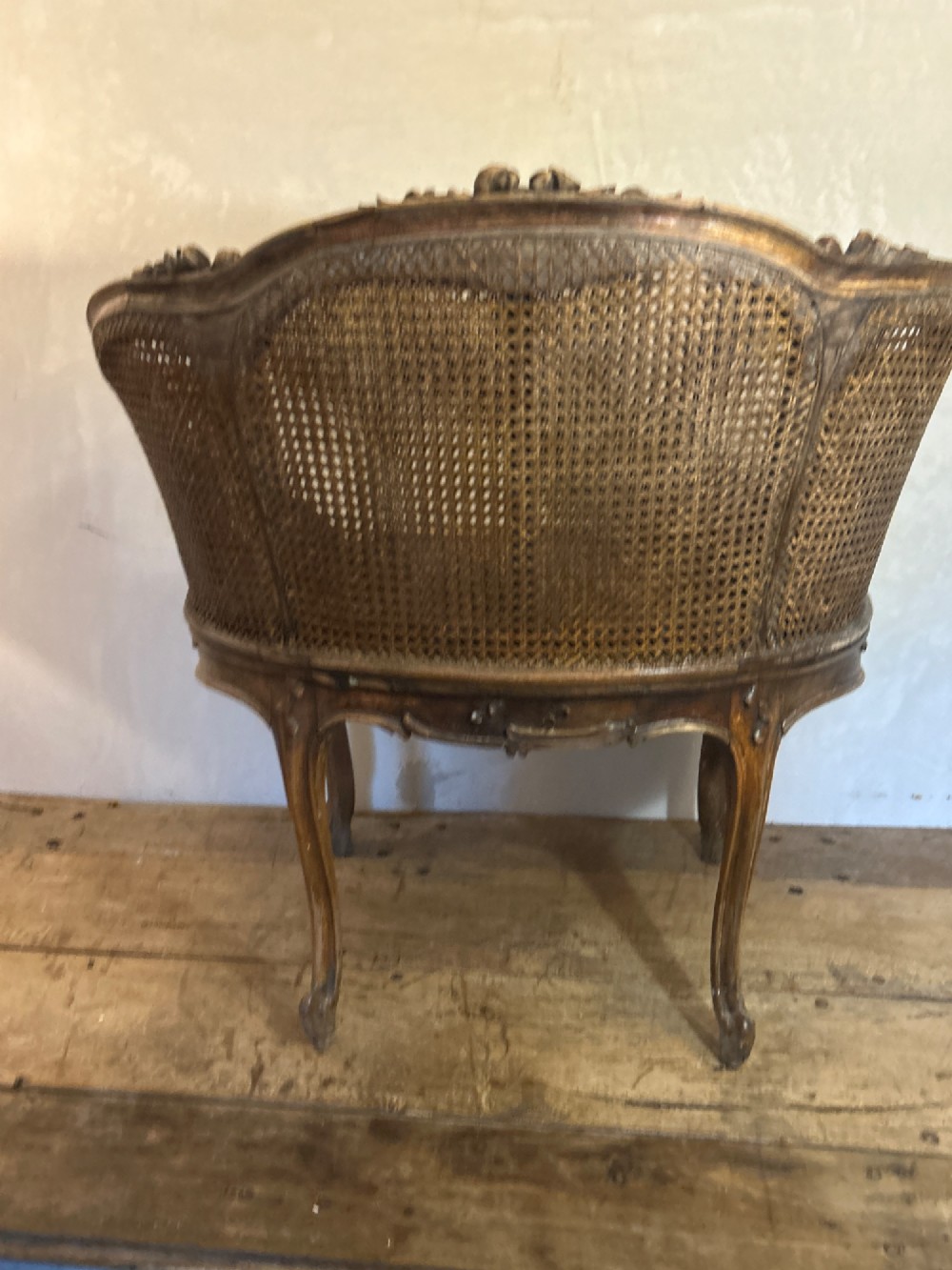 A 19th-century French Louis XV style Corbeille armchair featuring a curved hand-woven cane backrest, carved wooden frame with cabriole legs, and a beige upholstered seat cushion. View XI