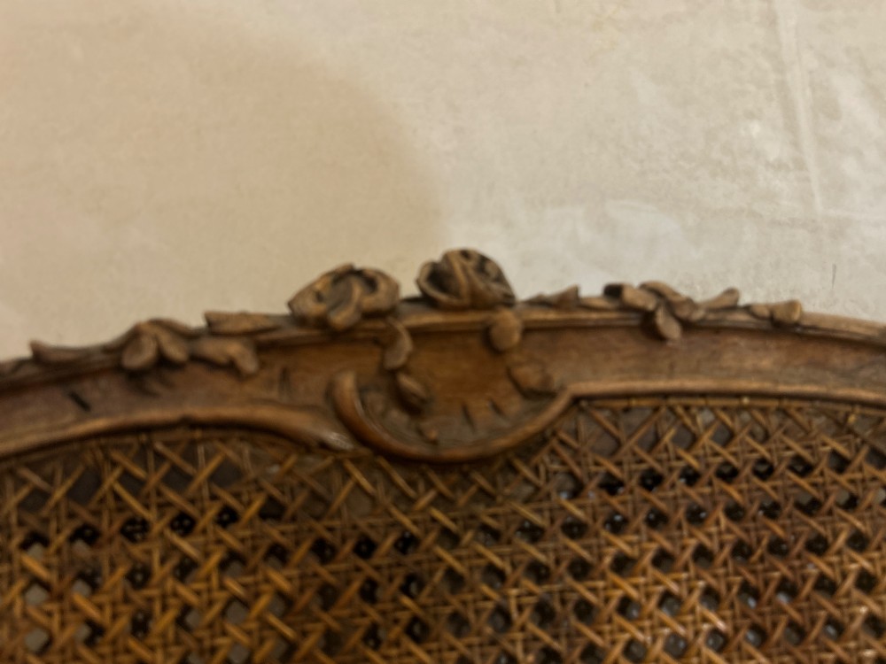 A 19th-century French Louis XV style Corbeille armchair featuring a curved hand-woven cane backrest, carved wooden frame with cabriole legs, and a beige upholstered seat cushion. View XII
