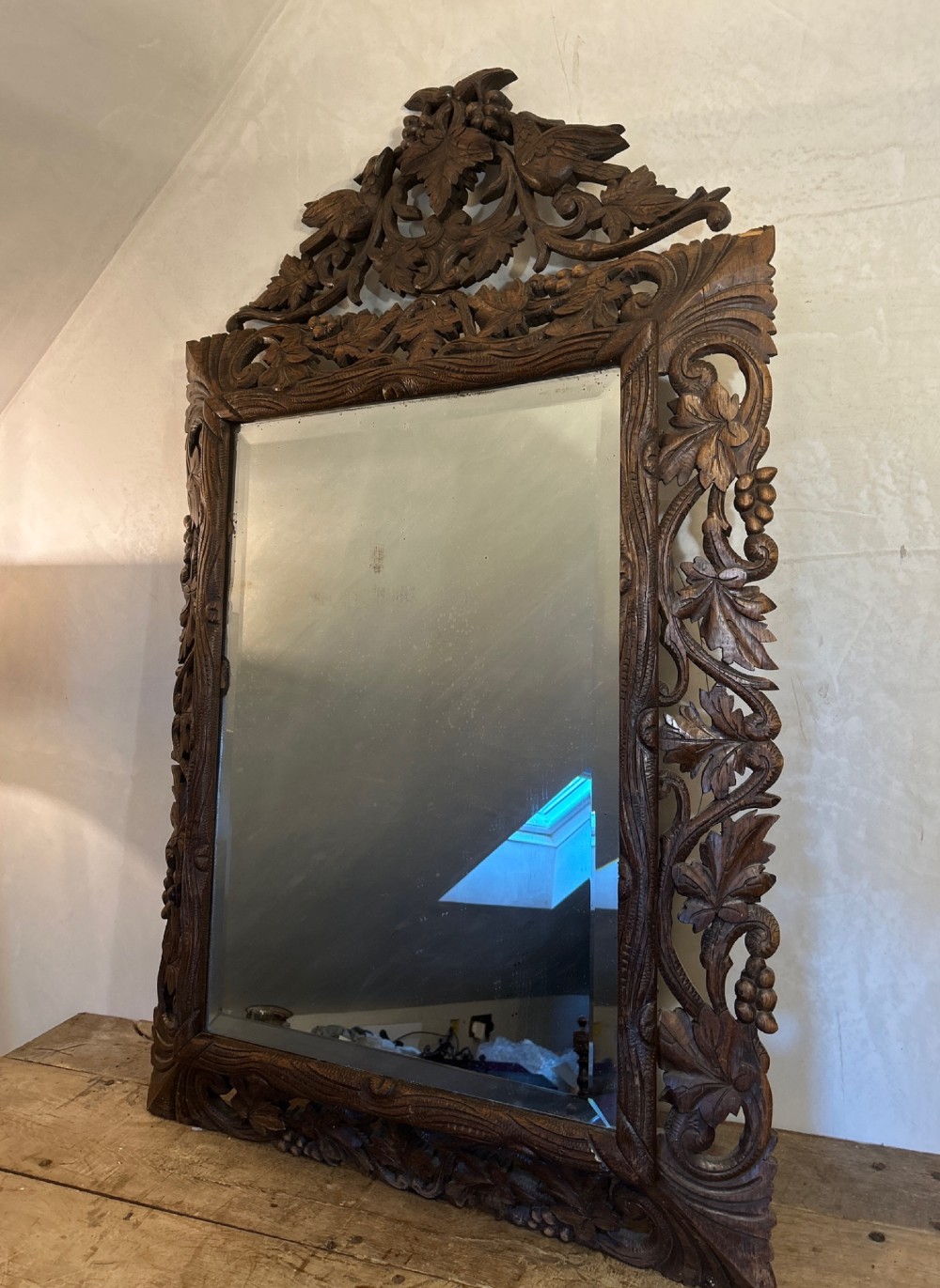 An ornate French oak wall mirror featuring intricate hand-carved leaf and grapevine motifs around a rectangular glass plate.