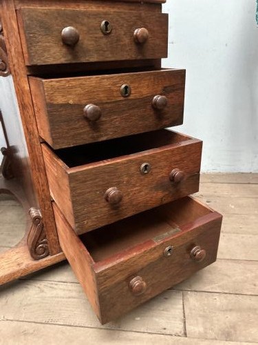 A Regency rosewood Davenport desk featuring an inclined leather-inlaid writing slope, a spindle top rail, side drawers, and turned front columns. View X